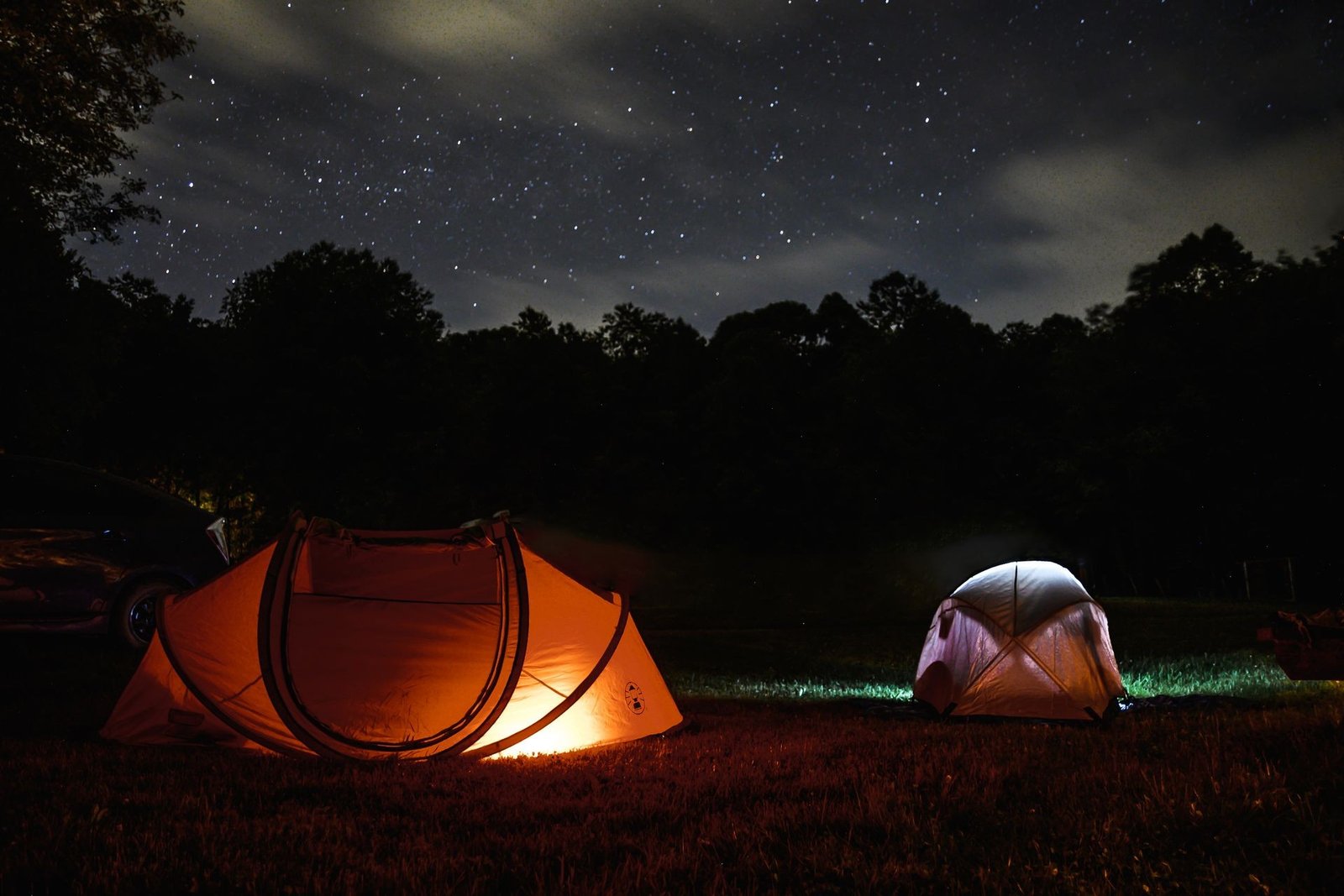 Tents lit up at night among the CoBeAc pines